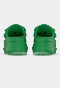 Green clogs with a textured finish, dual cut-out holes for ventilation, and an adjustable heel strap, designed for comfort and ease of use.
