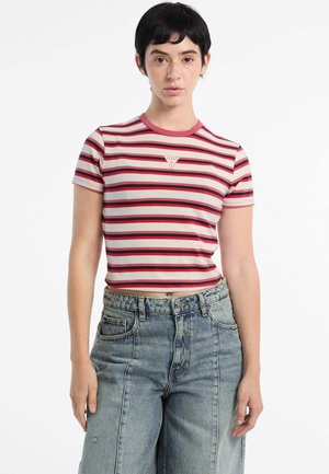 Gestreiftes Kurzarmoberteil mit pinken, roten und weißen Streifen, das ein kleines Logo auf der Brust zeigt. Kombiniert mit hochgeschnittenen Jeans.