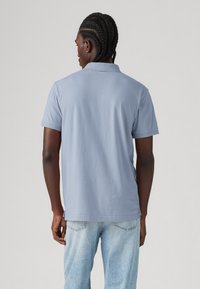 Light blue polo shirt made from soft cotton, featuring a classic collar and short sleeves, paired with light denim jeans.