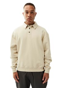 Beige pullover sweatshirt with a collar, three buttons, and ribbed cuffs. Soft material with a relaxed fit. Minimalistic design.
