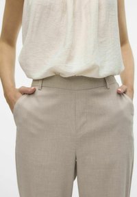 Beige lněné kalhoty s bočními kapsami, elegantním designem a hladkou texturou, kombinované s lehkým, volně splývavým topem.