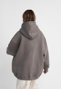 Übergroßer grauer Hoodie aus weichem Material, mit großer Kapuze, überschnittenen Schultern und einem gerippten Saum für eine lässige Passform.