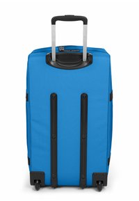 Blauer Hartschalenkoffer mit ausziehbarem Griff, vier Rollen, schwarzen Akzenten und strukturierter Oberfläche. Auf der Rückseite befinden sich vertikale schwarze Streifen.