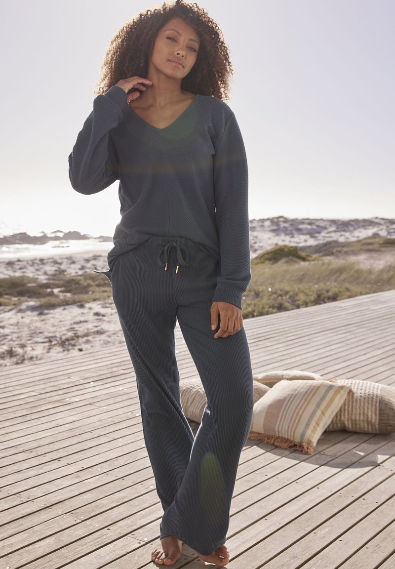 Marineblaues Ripp-Loungewear-Set mit einem V-Ausschnitt und langen Ärmeln sowie Pant mit Kordelzug, aus weichem Material gefertigt. Vertikale Musterdetails.