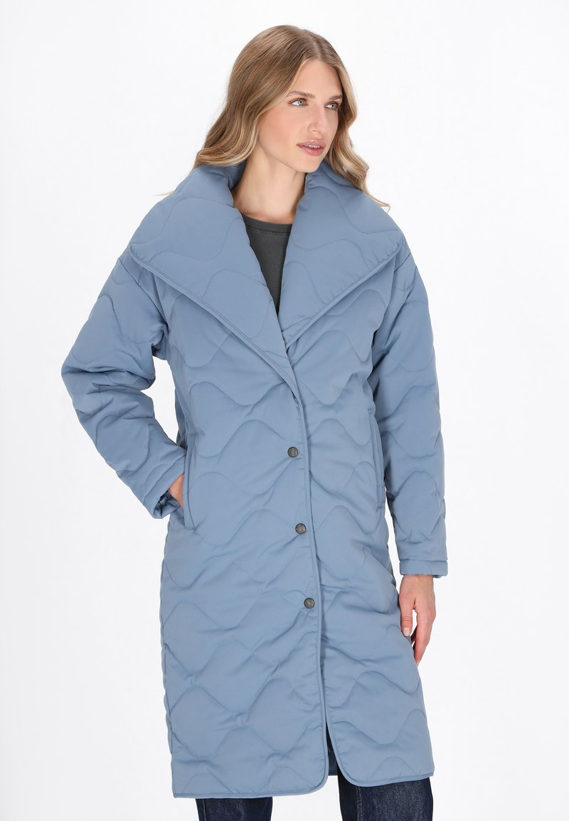 Cappotto blu imbottito con ampio colletto, maniche lunghe e bottoni frontali. Presenta una texture liscia e un motivo ondulato sulla stoffa.