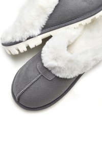 Gray slippers with a soft white faux fur lining, featuring a stitched seam and textured rubber sole for grip.