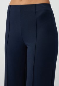 Navy blue wide-legged trousers made of soft fabric, featuring front pleats and a smooth texture, designed for a comfortable fit.