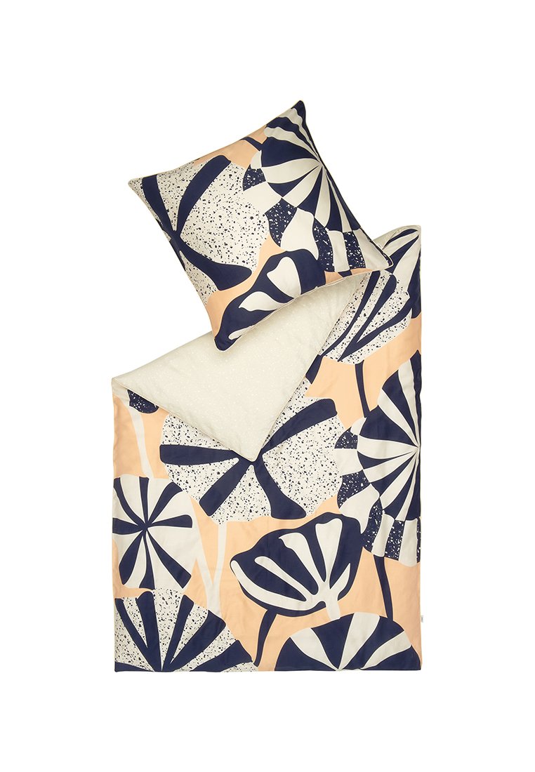 Juego de ropa de cama impreso con grandes patrones de hojas en color azul marino oscuro y lunares sobre un fondo durazno; presenta una parte inferior blanca texturizada.
