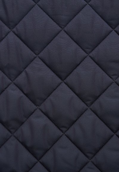 Σκούρο ραμμένο ύφασμα με ραφές σε σχήμα ρόμβου και ελαφρώς επενδυμένη υφή σε κοντινή λήψη.