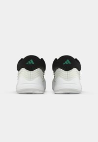 Black and white athletic shoes with textured fabric, green accents, and pronounced heel contours, featuring a smooth sole and layered design.