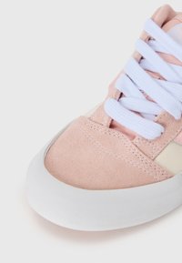 Roosa seemist sneaker valge kummist tallaga. Omab valgeid paelu ja kontrastset kreemjat paneeli. Sile tekstuur, ümar varba disain.
