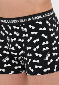 Boxer neri caratterizzati da un motivo ripetuto di occhiali da sole bianchi. Coulisse elastica con etichetta 'KARL LAGERFELD'. Tessuto morbido.