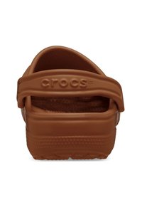 Sandales Crocs marron à enfiler, dotées d'une large sangle, d'un intérieur texturé et d'un pied perforé. Fabriquées en matériau résine léger.
