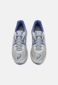 Light gray athletic shoes with blue accents, mesh material, rounded toe, cushioned collar, and flat laces. Features logo on the side.