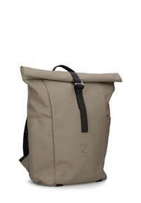 Sac à dos beige à rabat enroulable en matériau imperméable, avec des bretelles noires, une texture géométrique sur les côtés et un logo à l'avant.