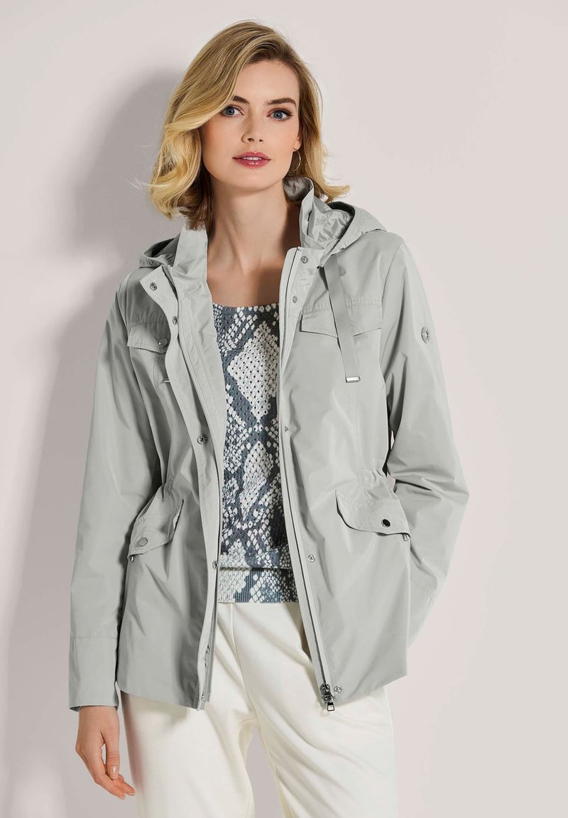 Hellgraue wasserdichte Jacke mit Kapuze, ausgestattet mit zwei Fronttaschen, verstellbarem Kordelzug und einer glatten Stoffstruktur.