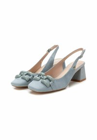 Zapatos de ante azul claro con tira trasera, puntera triangular y tacón de bloque grueso. Detalle decorativo de moño gris en la parte frontal.