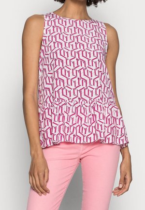 Top peplum senza maniche in tessuto bianco con un motivo geometrico rosa. Texture morbida con orlo svasato, abbinato a pantaloni rosa.
