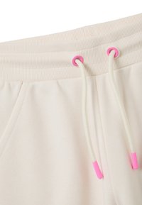 Lichtbeige sweatpants gemaakt van zachte stof, met een geribde tailleband, witte trekkoorden en roze aglets.