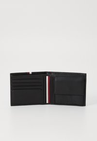 Portefeuille en cuir noir avec plusieurs emplacements pour cartes, une fenêtre ID transparente et un accent de ruban rayé en rouge, blanc et marine.