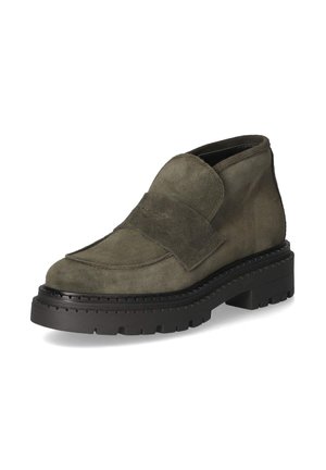 Massiver dunkelgrüner Wildleder-Slipper mit dicker schwarzer profillierter Sohle und breitem Riemen über dem Vorderfuß, schräg auf weißem Hintergrund gezeigt.