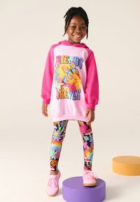 Rózsaszín pulóver színes "Barátok örökre" grafikával és élénk virágdíszekkel, mintás leggingekkel párosítva, melyeken virágok és szivárványok láthatók.