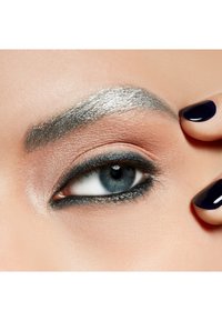 Silberne Augenbrauen-Make-up mit definierter Form, schwarzer Eyeliner, schimmernder Lidschatten und einem blauen Auge. Schwarzer Nagellack auf den Fingern.