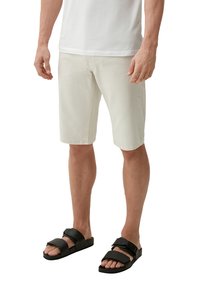 Helle beige Baumwollshorts, knielang, mit geradem Schnitt. Kombiniert mit schwarzen verstellbaren Sandalen. Einfaches, lässiges Design.