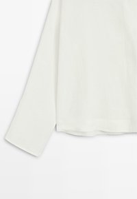 Langærmet hvid skjorte med lige pasform og enkelt design på en ensfarvet baggrund.