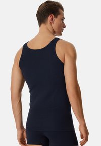 Débardeur marine en coton doux, avec un col rond et de larges bretelles. Texture lisse, design ajusté.