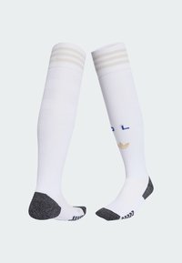 Hvide knæhøje atletiske sokker med beige striber øverst, sort forstærket hæl og tå, samt blå og beige logodetaljer på siderne.