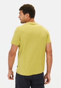 Korte mouwen, ronde hals t-shirt in lichtgeel katoen. Gladde textuur met een ontspannen pasvorm, zichtbare stiksels bij de hals en mouwen.