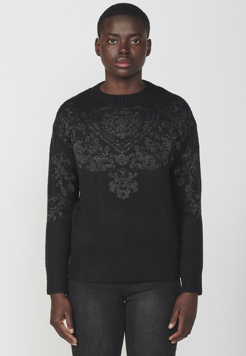 Maglione nero lavorato a maglia con un motivo floreale testurizzato sul petto, colletto rotondo e polsini e orlo a costine. Tessuto morbido.