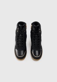 Czarne sneakersy za kostkę z mieszanką matowych i błyszczących faktur, z złotymi akcentami, perforowanymi panelami i detalem zamka z boku.