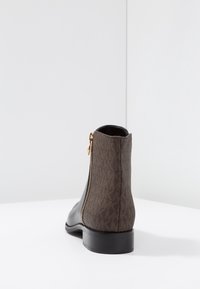 Stivale alla caviglia in pelle nera con retro in tessuto marrone a motivo, zip dorata laterale e tacco basso texturizzato.