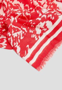 Écharpe rouge en tissu léger avec un motif abstrait blanc et des bords à franges. Elle présente une texture en chevrons et des rayures superposées.