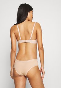 Nude lingerie set featuring a simple design with adjustable straps, soft fabric, and minimalistic detailing.
