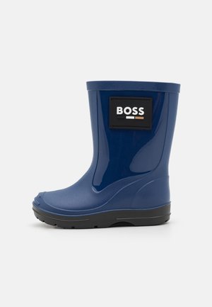 Botte de pluie en caoutchouc bleu avec semelle noire et patch logo "BOSS" sur le dessus, photographiée sur fond blanc uni.
