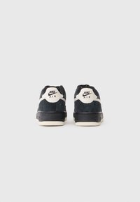Nike Air kedas ar tumši zilas zamšādas augšdaļu, krēmkrāsas akcentiem un melnu gumijas zoli. Iespējas izšūts logo uz papēža.