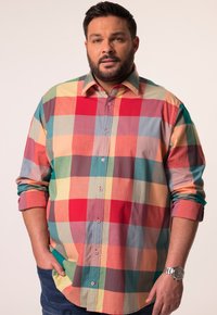 Camisa de cuadros multicolor que presenta grandes bloques de rojo, amarillo, verde y azul. Diseño de botonadura con cuello puntiagudo y mangas enrolladas.