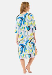 Kaftán liviano con estampado que presenta un diseño abstracto multicolor en azul, verde y negro. Mangas cortas y aberturas laterales para facilitar el movimiento.