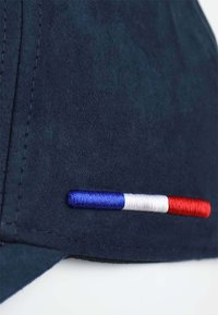 Marinekappe mit einer gestickten Akzentierung aus blauen, weißen und roten Streifen an der Seite. Hergestellt aus strukturiertem Stoff mit sichtbaren Nähdetails.