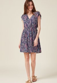 Marineblaues Kleid mit lebhaften, mehrfarbigen Paisleymustern. V-Ausschnitt, kurze Ärmel und elastischer Bund. Leichter Stoff, knielanger Saum.