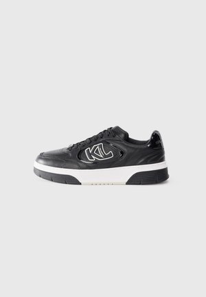 Svart lær sneakers med hvit såle, med en fremtredende logo på siden, teksturert overdel og kontrasterende detaljer på hælen.