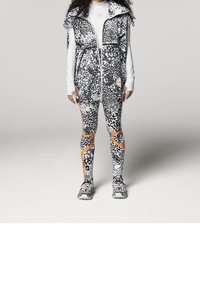 Svart-vitt leopardmönstrat träningslinne med dragkedja, kombinerat med matchande leggings med orange detaljer och texturerad tyg.