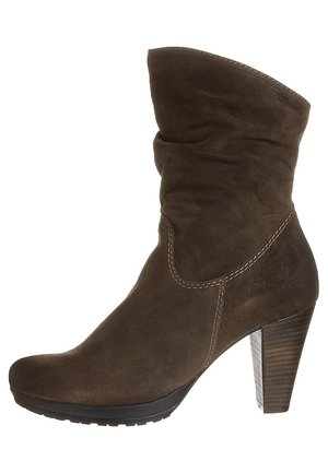 Brown suede ankle boot with slouchy upper, curved top, and 3-inch wooden heel. Features subtle stitching along seams and rubber sole.