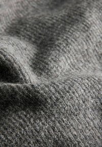 Tessuto grigio texturizzato che presenta una superficie morbida e pelosa con un motivo a coste, mettendo in mostra variazioni di tonalità e profondità.