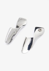 Silverskoohornsett med en flytende, buet design. Glatt, reflekterende overflate med avrundede kanter. Kompakt, ergonomisk form for enkel håndtering.