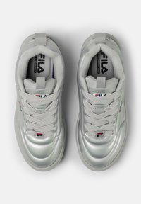 Sneakers argento con una superficie lucida e texturizzata. Presentano un colletto imbottito, lacci intrecciati e un logo del brand sulla linguetta e sul lato.