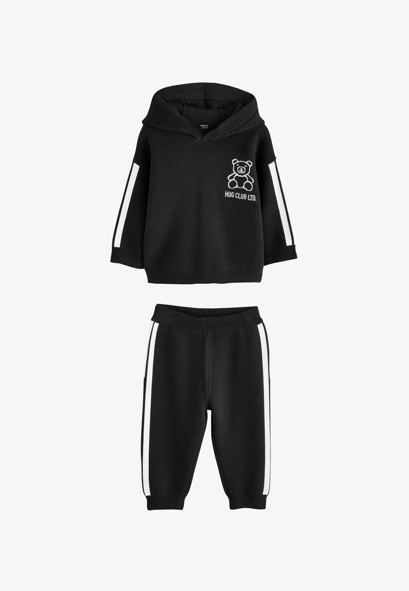 Must sceen koosnev beebide komplekt, millel on kapuutsiga sviiter, millel on valge karu ja tekst "HUG CLUB LTD." ning millele on sobitatud valgete külgtriipudega püksid.